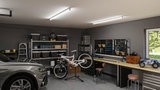 Helle Werkstatt mit LED-Deckenleuchten, Werkbank, Werkzeugwand und Fahrrad in moderner Garage.
