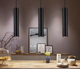 Three black aluminum pendant lights above wooden table with dishes and vase, modern LED lighting