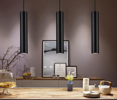 Three black aluminum pendant lights above wooden table with dishes and vase, modern LED lighting