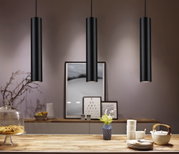 Three black aluminum pendant lights above wooden table with dishes and vase, modern LED lighting