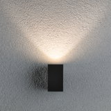 Zwarte metalen LED-wandlamp met warm wit licht op gestructureerde grijze muur
