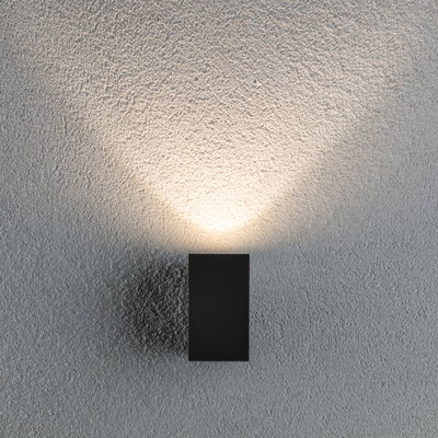 Zwarte metalen LED-wandlamp met warm wit licht op gestructureerde grijze muur