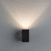 Black metal LED wall light with warm white glow on textured grey wall for modern lighting