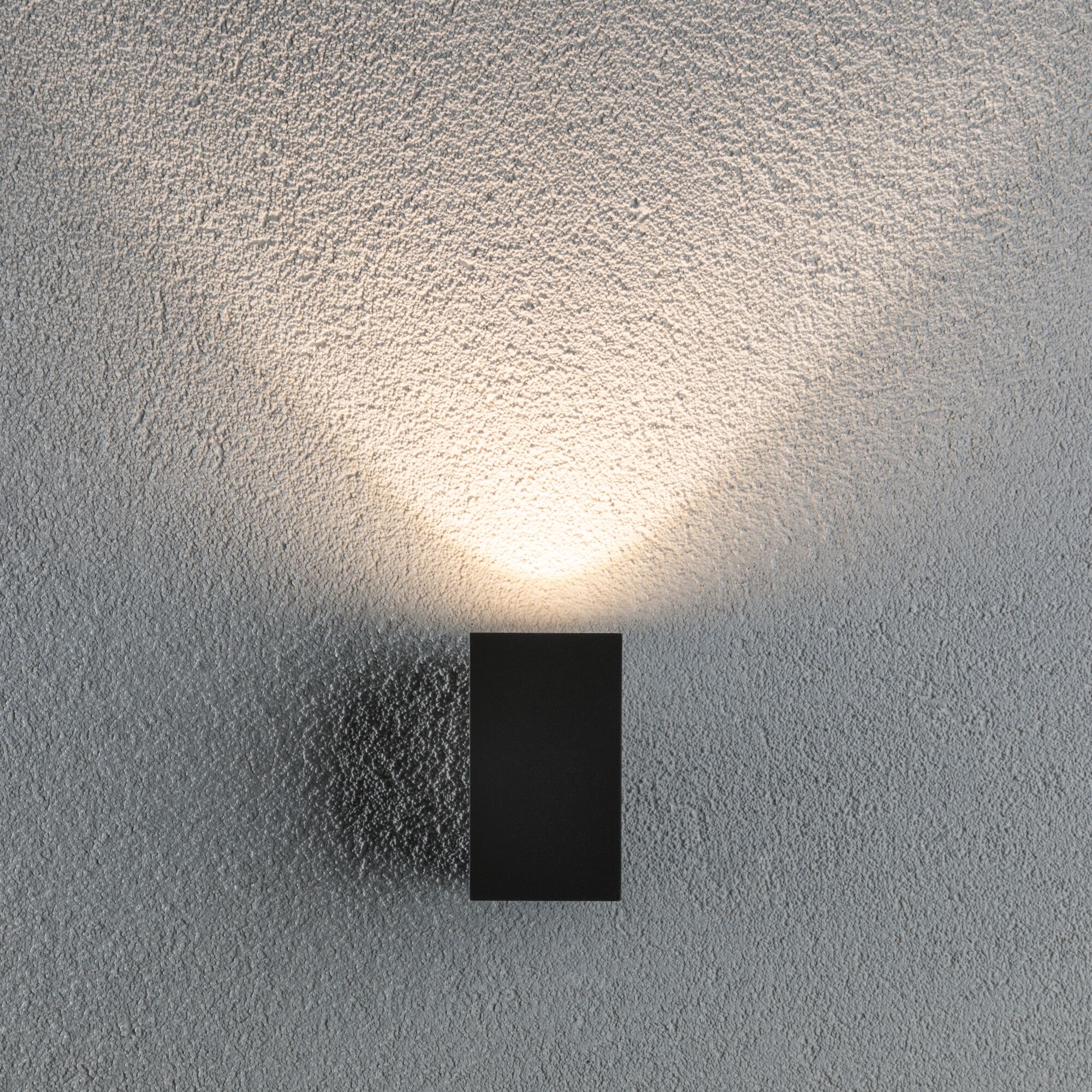Schwarze LED-Wandleuchte aus Metall mit warmweißem Licht an strukturierter grauer Wand