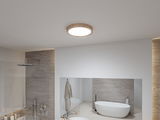 Round ceiling light with wooden frame in modern bathroom featuring bathtub and shower