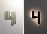 Moderne Hausnummer 4 aus schwarzem Material mit weißer LED-Beleuchtung an strukturierter Wand.
