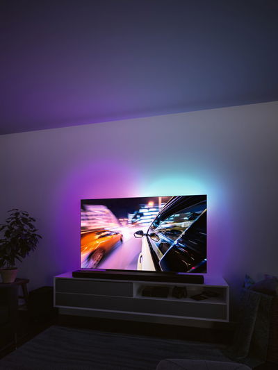 Moderne stue med tv og farvet LED-baggrundsbelysning til stemningsfuld belysning