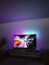 Moderne stue med tv og farvet LED-baggrundsbelysning til stemningsfuld belysning