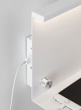 Applique murale blanche moderne avec bouton rotatif en aluminium et port de charge USB près d’un smartphone.