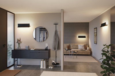 Moderne stue med sorte væglamper, beige sofa og gråt skænk til stilfuld belysning