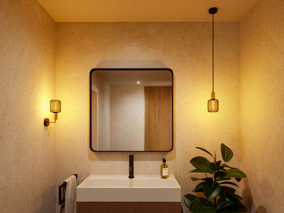 Modern bathroom with square mirror, white sink, and warm LED wall and pendant light in metal design.