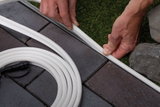 Weiße flexible LED-Lichtleiste wird zwischen Pflastersteinen und Rasen verlegt für Gartenbeleuchtung