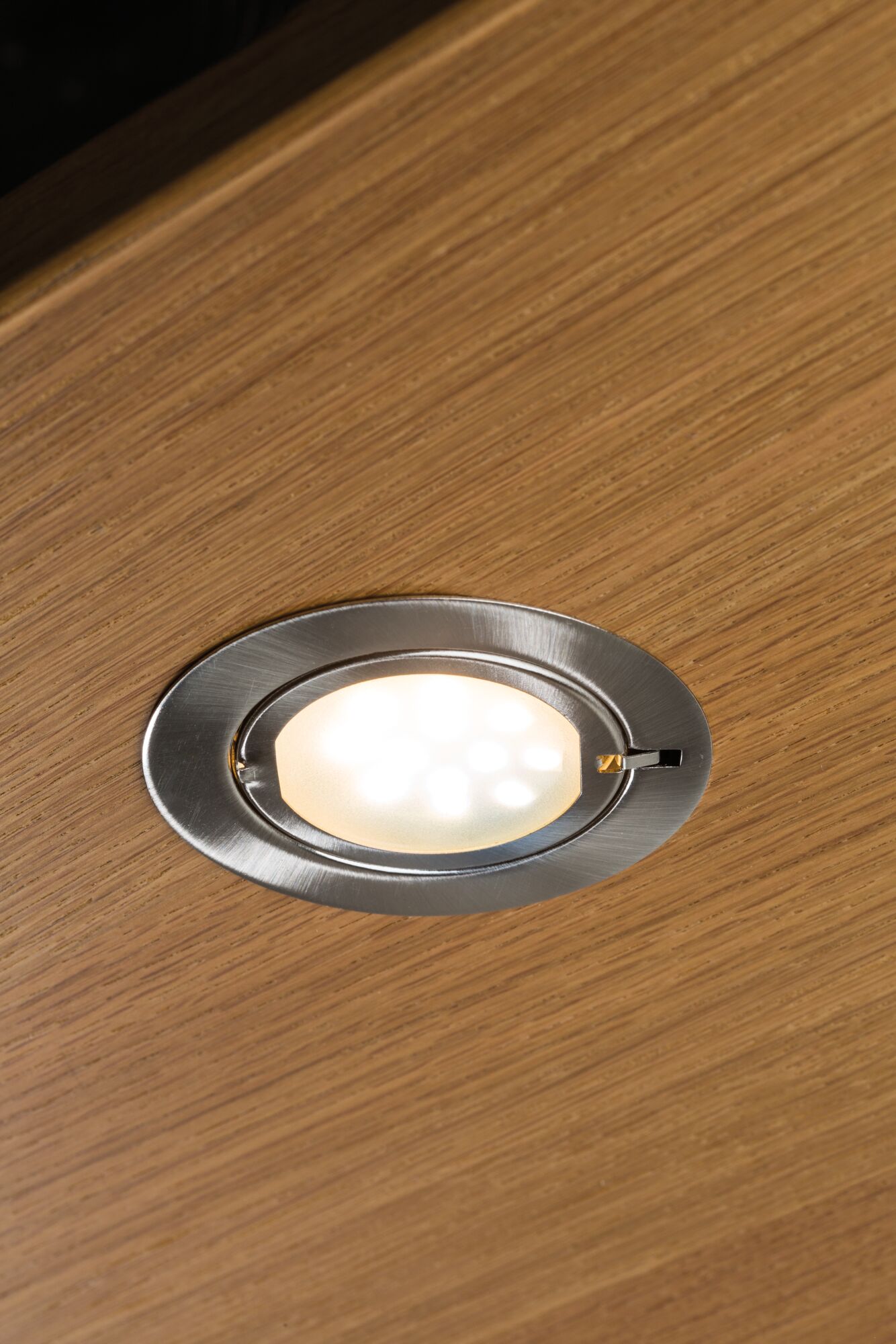 Round recessed LED spotlight in brushed stainless steel mounted in wooden ceiling for accent lighting