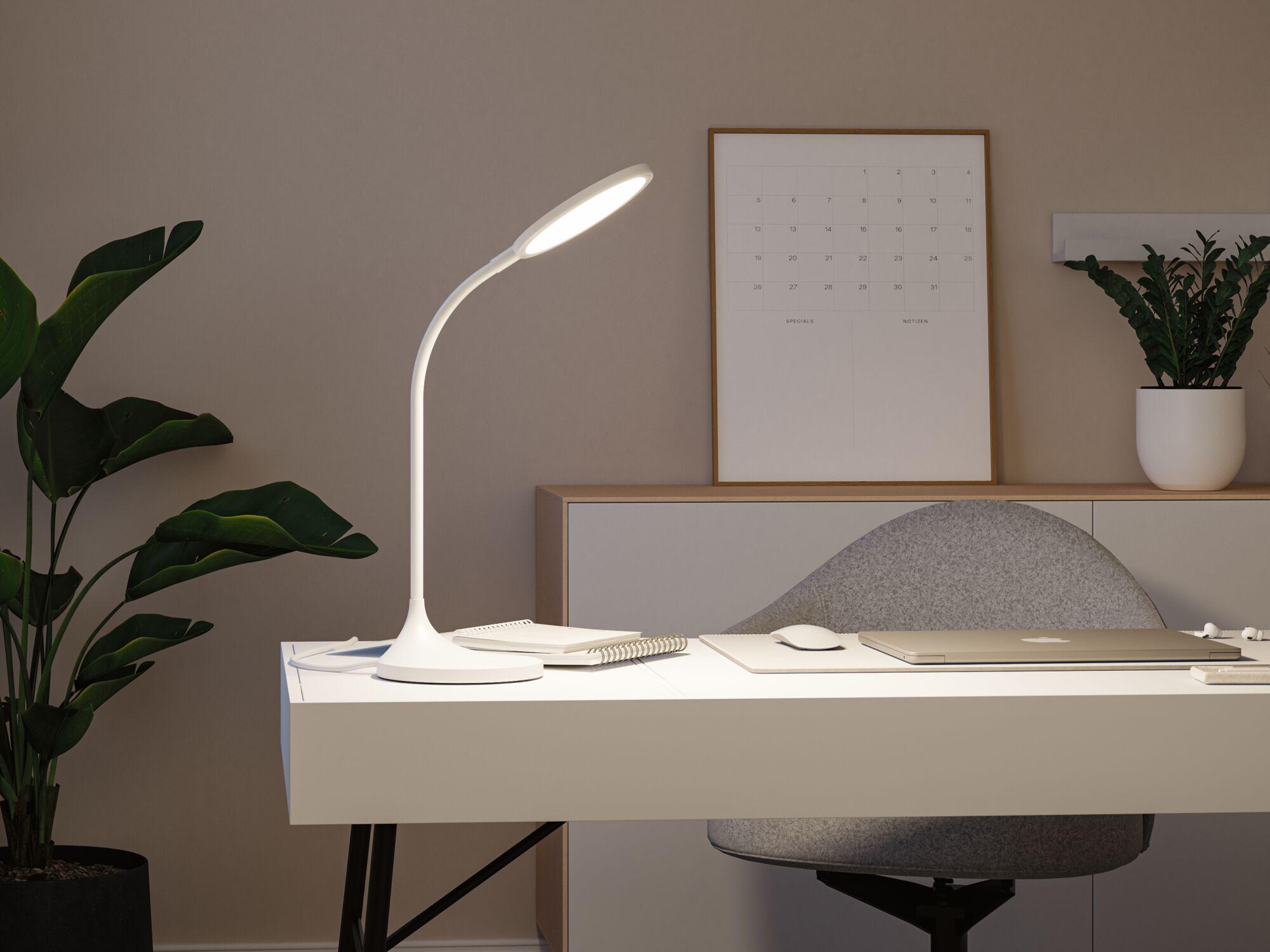 White LED desk lamp with flexible neck on modern workspace with laptop and notebook