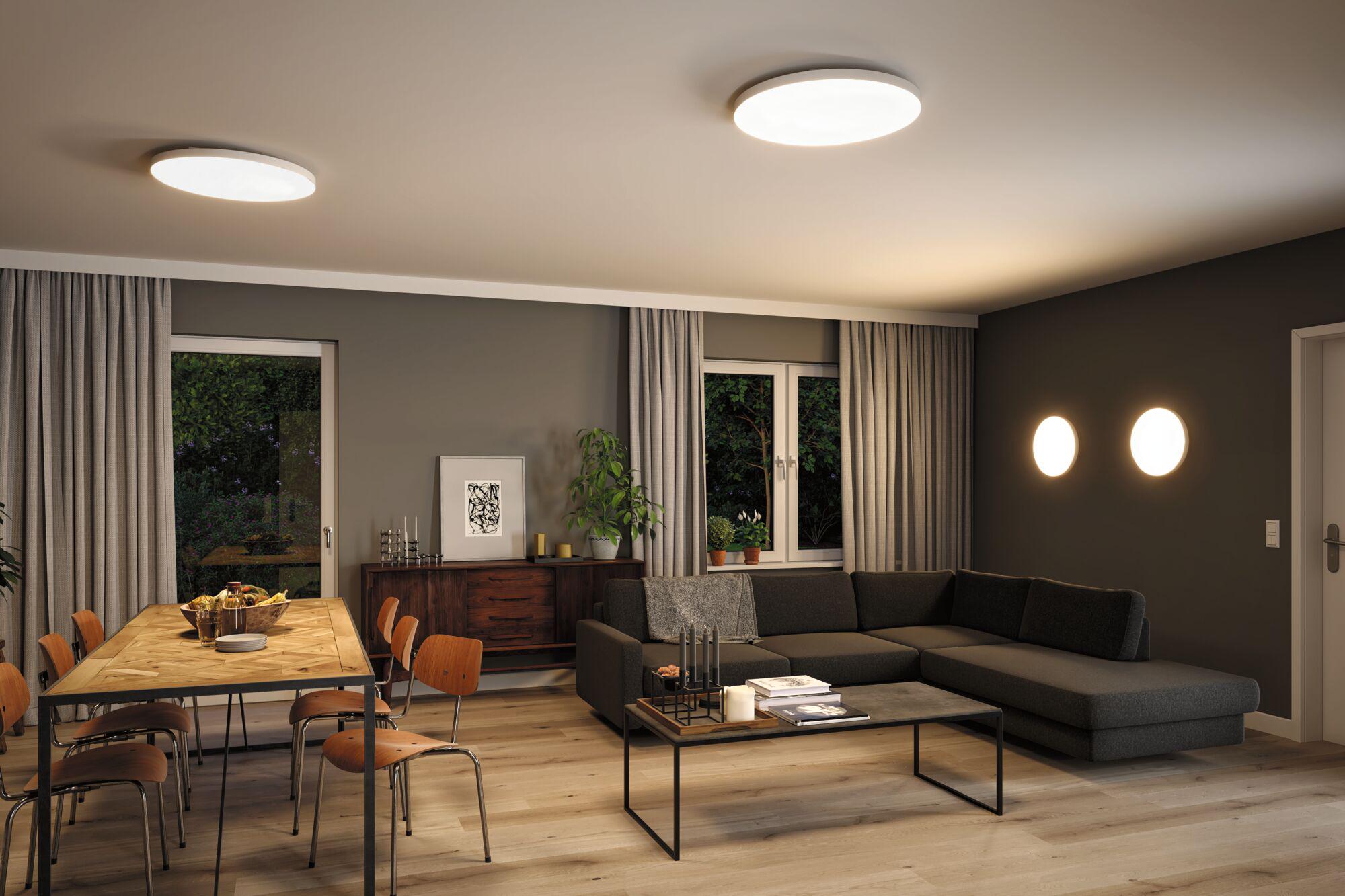 Modern living room with round white plastic ceiling and wall lights, warm LED lighting for ambiance.