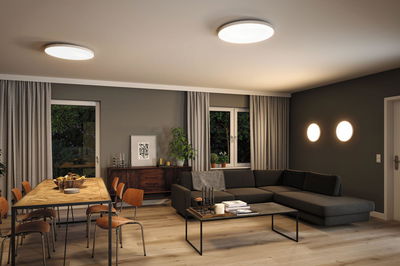 Moderne stue med runde hvide lofts- og væglamper i plastik, varm LED-belysning.