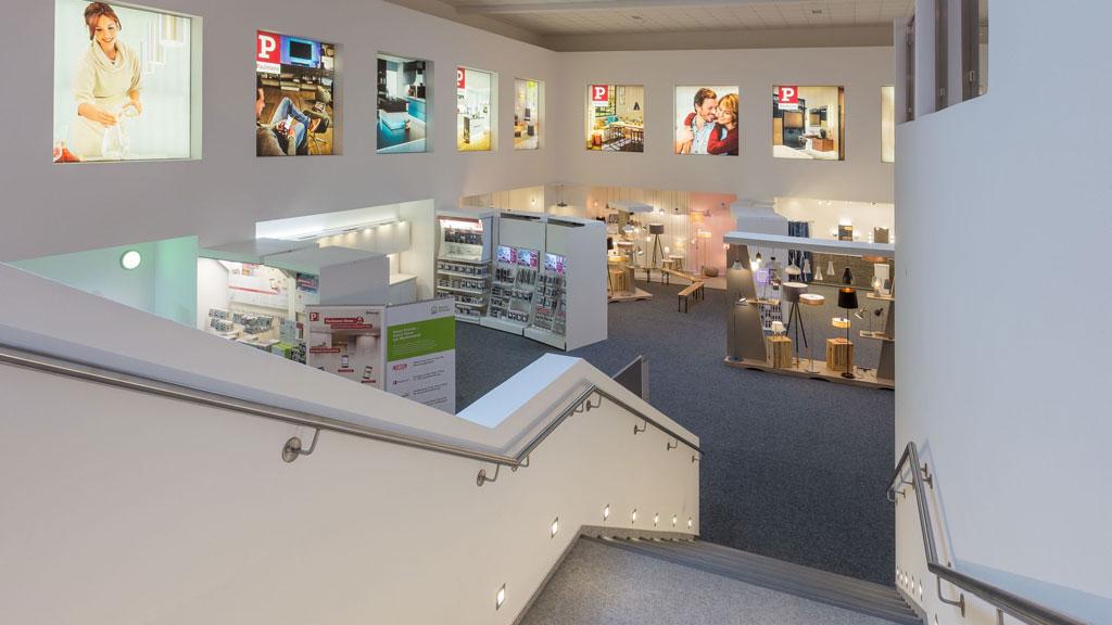 Intérieur d'une salle d'exposition moderne avec différentes solutions d'éclairage et images promotionnelles au mur.