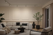 Modern living room with beige sofa, black and grey cushions, wooden and black coffee tables, plants, and ceiling spotlights