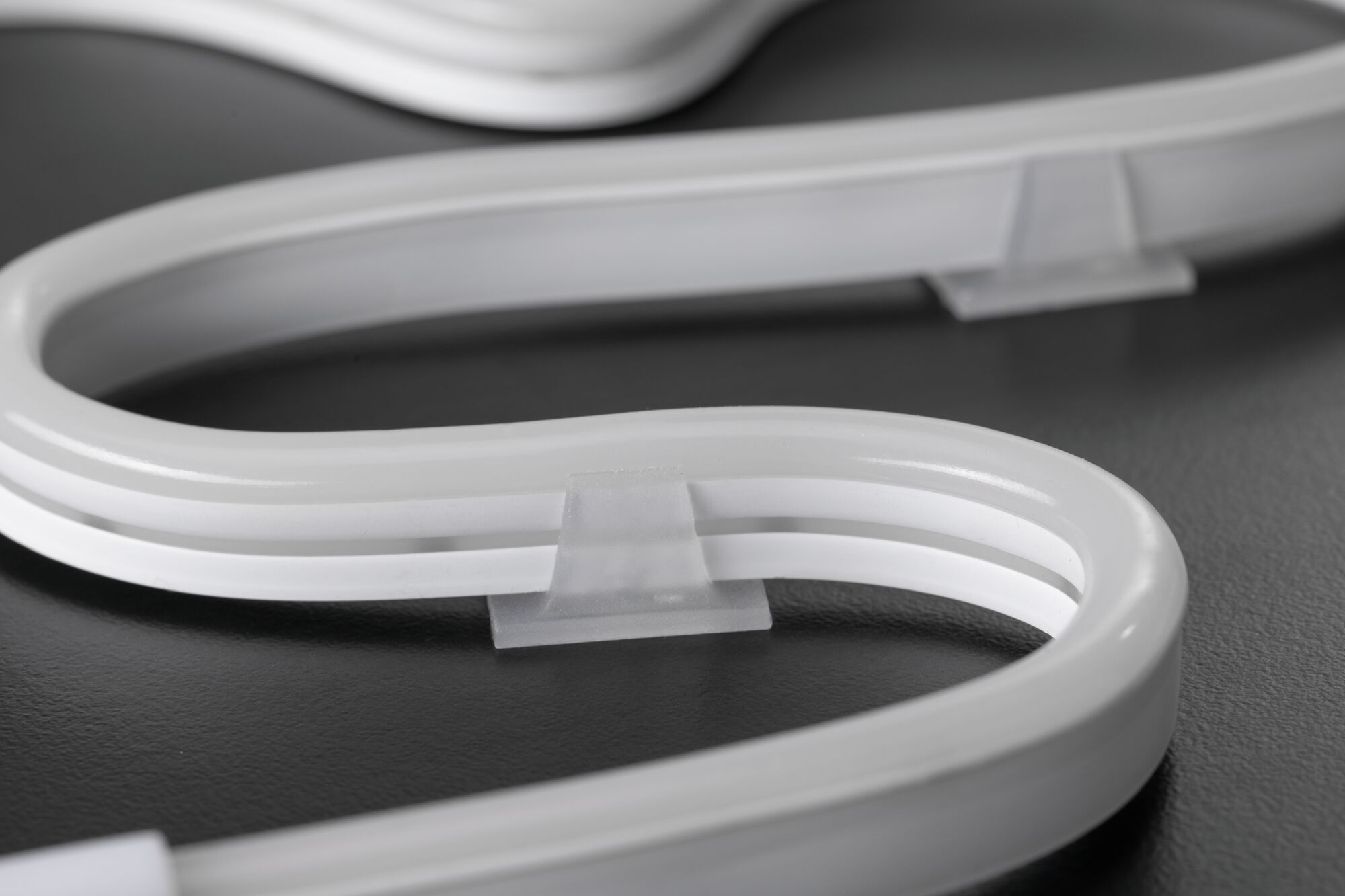 Flexible white LED neon light with transparent clip on dark surface for decorative lighting solutions