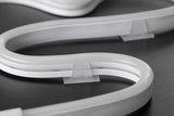 Flexibles weißes LED-Neonlicht mit transparenter Halterung auf dunklem Untergrund für dekorative Beleuchtung