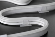 Bande lumineuse néon blanche flexible en plastique avec support sur surface sombre
