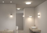 Modern bathroom with white glass and metal wall and ceiling lights providing stylish illumination