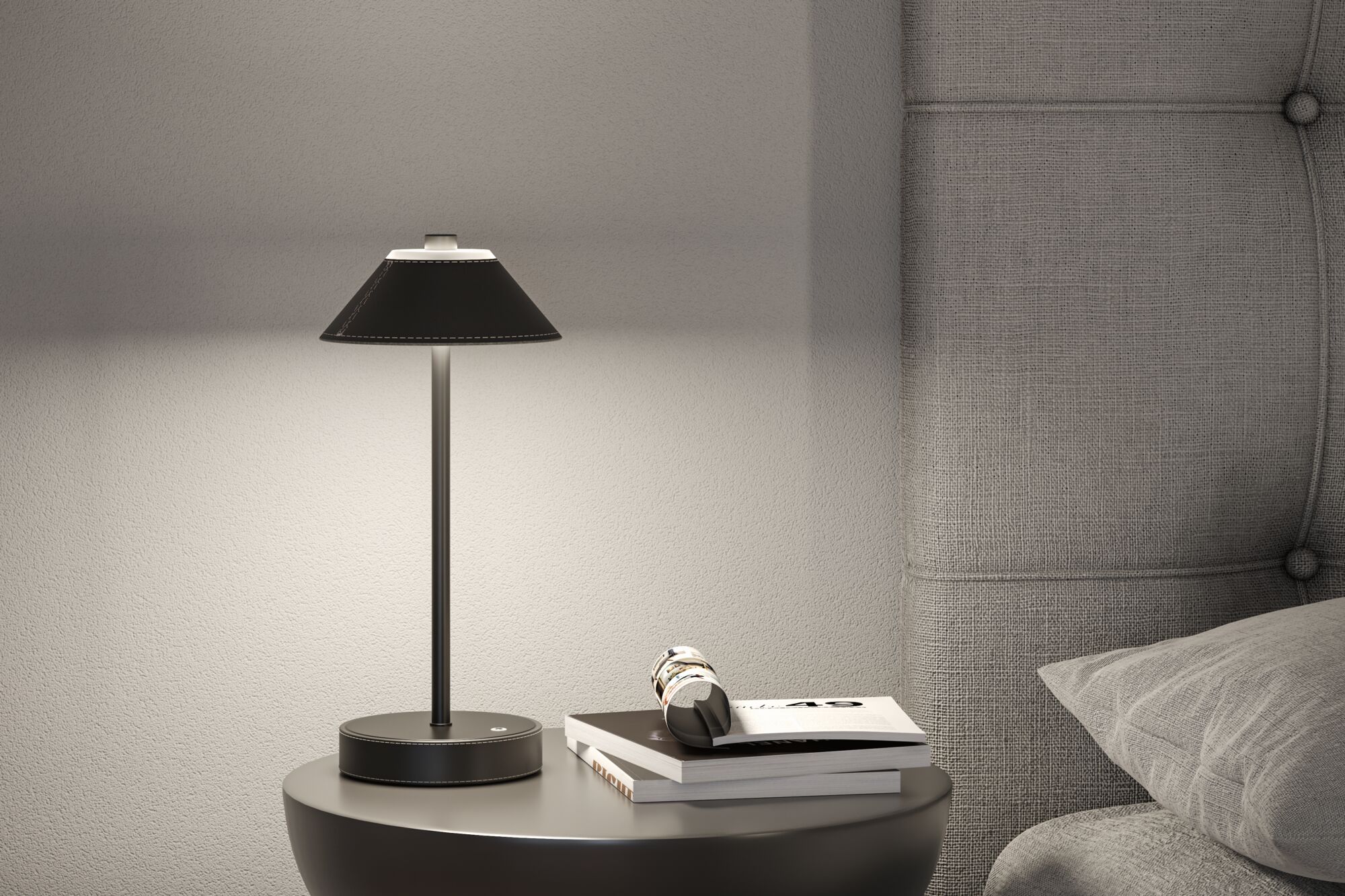 Modern black leather table lamp on round bedside table next to grey upholstered bed for bedroom lighting