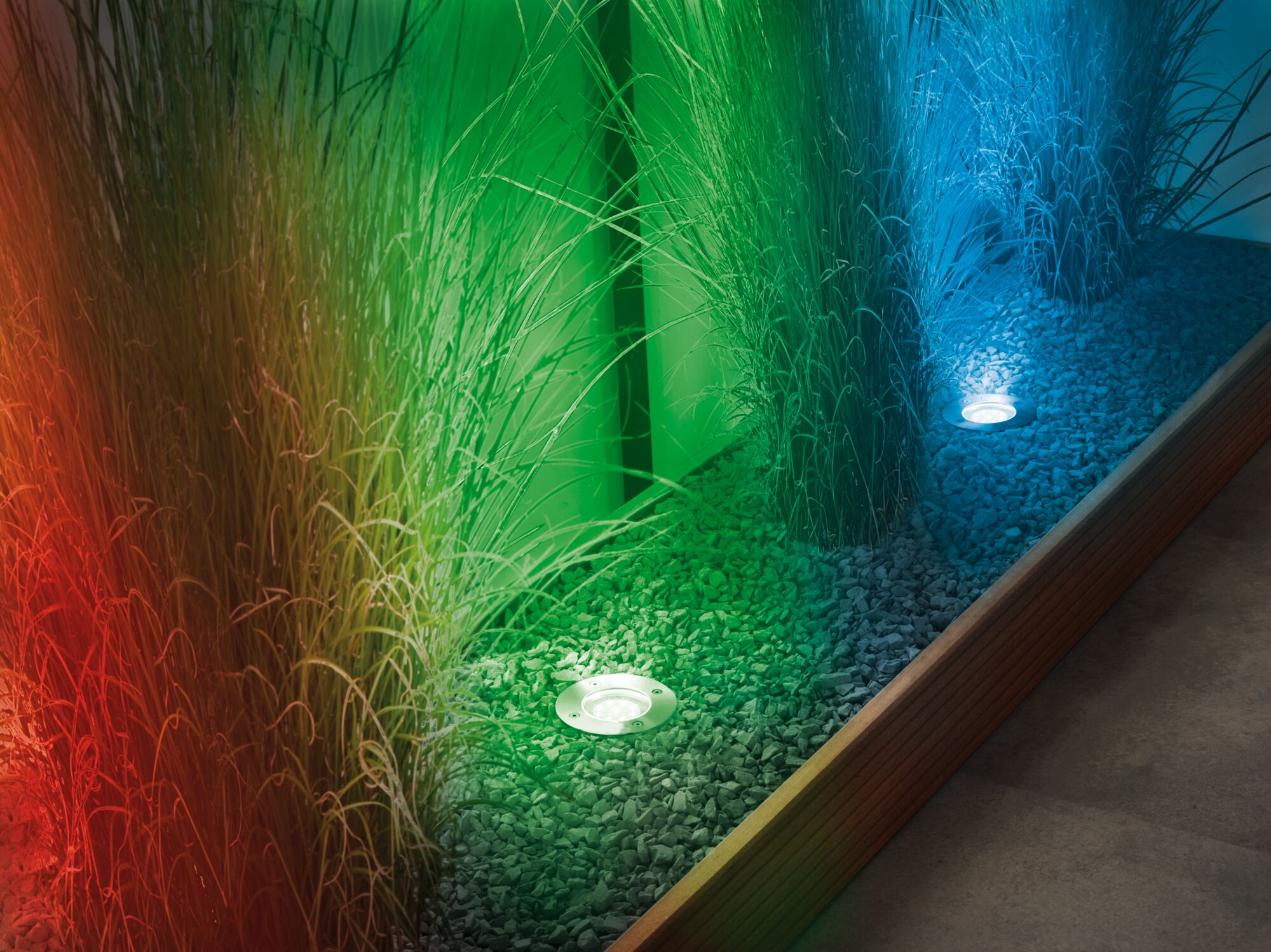 Eingelassene LED-Bodenleuchten in Edelstahl mit rotem, grünem und blauem Licht im Kiesbeet