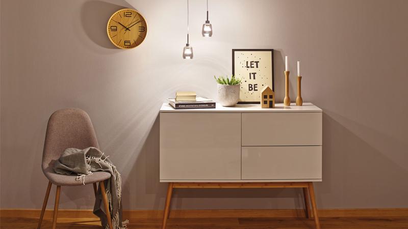 Moderne halverlichting met twee hangende glazen lampen boven een wit dressoir en houten stoel in warme sfeer