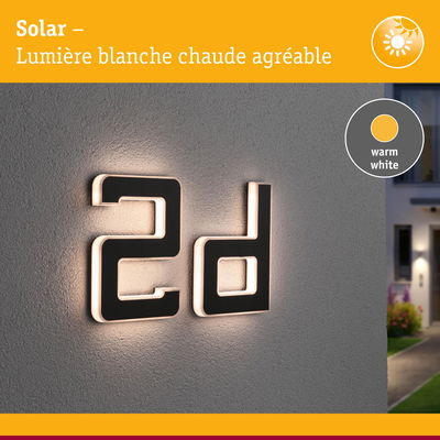 Numéro de maison 2d noir moderne avec éclairage LED blanc chaud sur mur gris extérieur