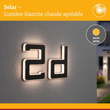 Numéro de maison 2d noir moderne avec éclairage LED blanc chaud sur mur gris extérieur