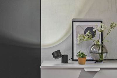 Zwarte metalen LED-tafellamp op wit dressoir met planten en modern ingelijst kunstwerk.