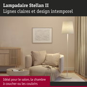 Lampadaire beige Stellan II avec abat-jour en tissu dans un salon avec fauteuil et buffet en bois