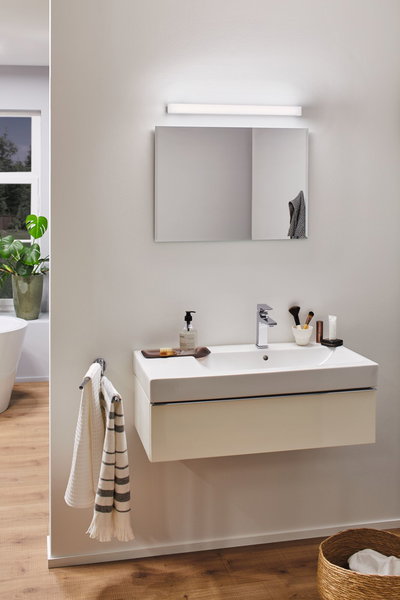 Moderne badkamer met witte wandgemonteerde wastafel, chromen kraan en LED-spiegelverlichting