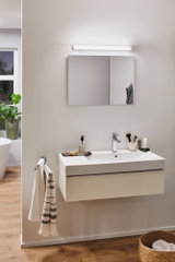 Modernes Badezimmer mit weißem Wandwaschbecken, verchromtem Wasserhahn und LED-Spiegelleuchte