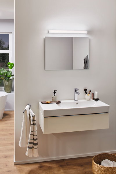 Modernes Badezimmer mit weißem Wandwaschbecken, verchromtem Wasserhahn und LED-Spiegelleuchte