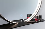 Round illuminated mirror with black metal shelf holding red and brown nail polish and cosmetic pencil