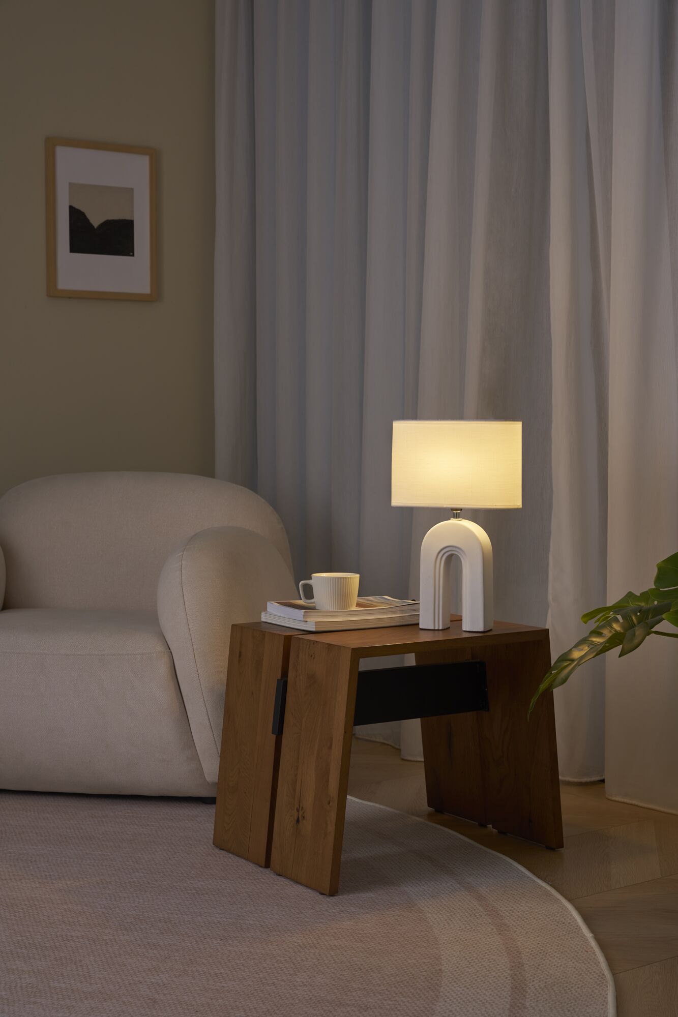 Lampe de table blanche moderne avec abat-jour en tissu sur table en bois à côté d'un canapé beige.
