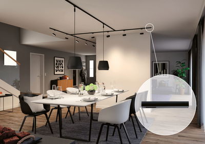 Modernes Esszimmer mit schwarzer Schienenbeleuchtung und weißen Stühlen auf Holzboden, LED-Spotlicht.