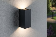 Black aluminium wall light with warm white up and down lighting on grey exterior wall