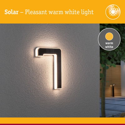 Solar-powered black LED wall light with warm white illumination for outdoor and garden lighting