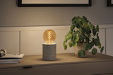 Modern table lamp with concrete cylindrical base and warm glowing bulb for ambient lighting in living spaces