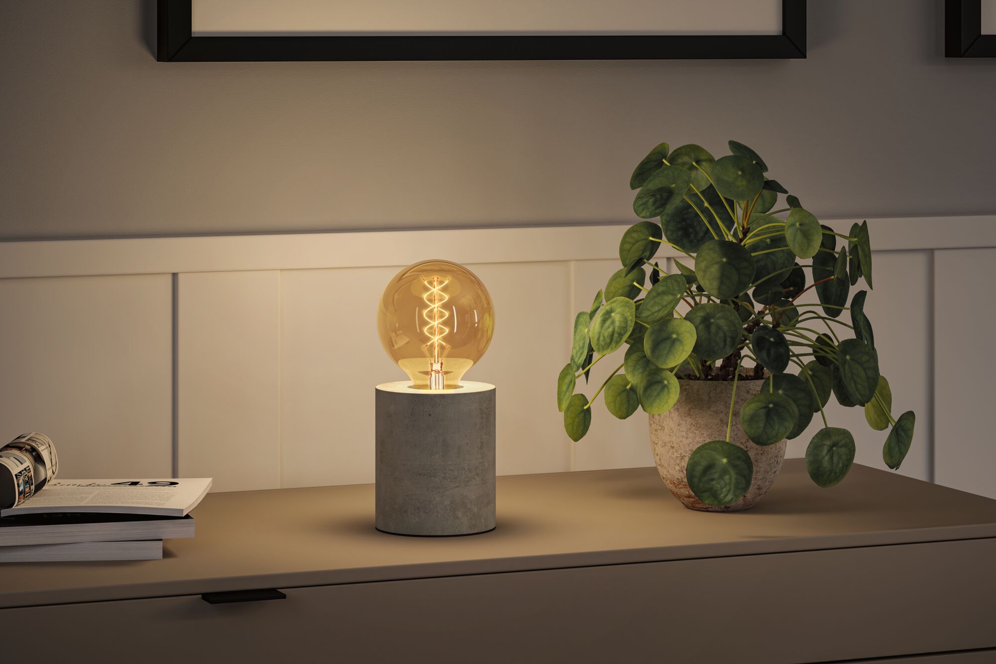 Moderne bordlampe med cylindrisk betonfod og varmt lysende pære til stemningsfuld belysning