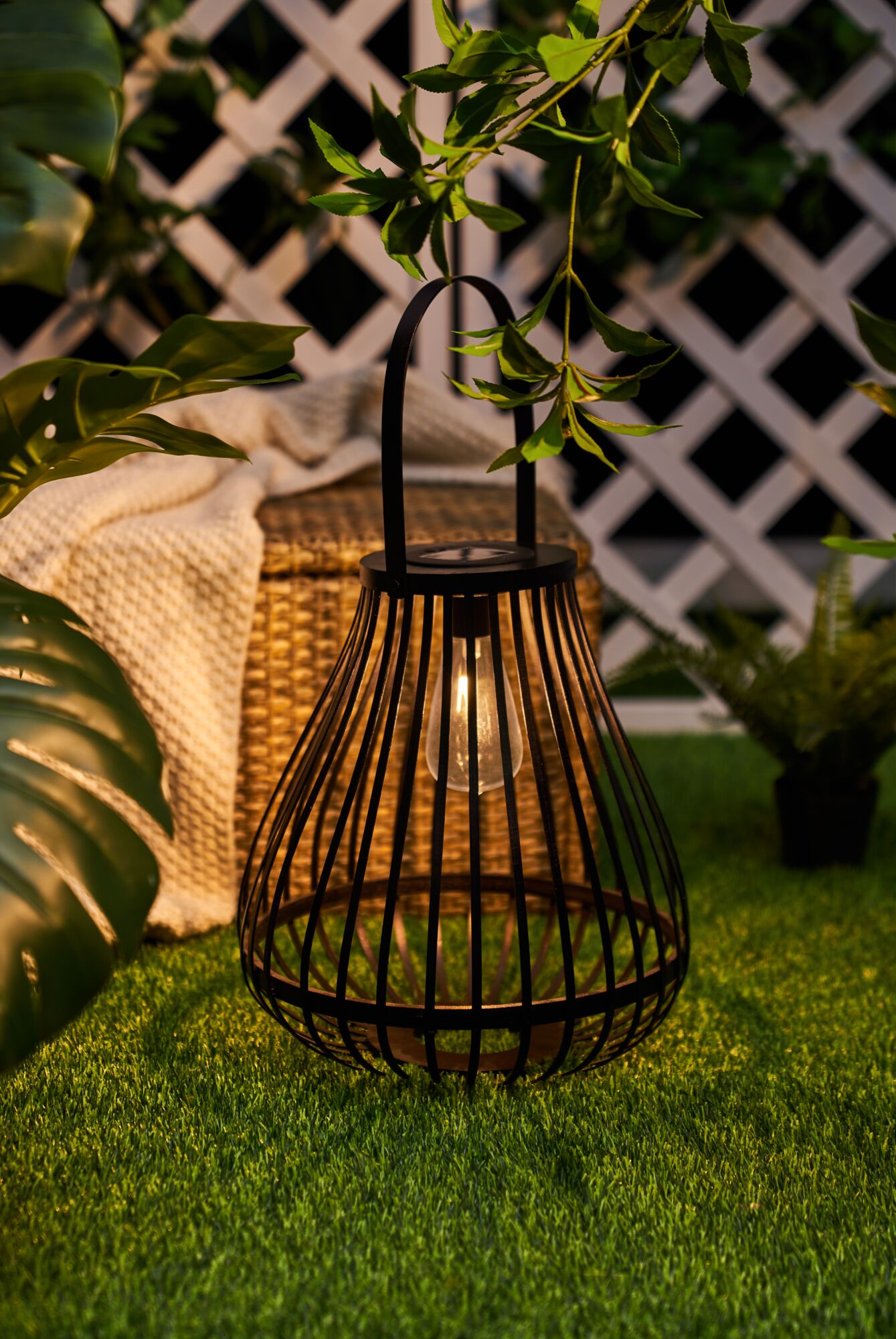 Schwarze Metalllaterne mit LED-Licht auf grünem Rasen, dekorative Gartenbeleuchtung im Außenbereich