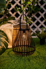Schwarze Metalllaterne mit LED-Licht auf grünem Rasen, dekorative Gartenbeleuchtung im Außenbereich