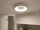 Ronde witte plafondlamp met warmwit LED-licht in moderne badkamer met natuurstenen wand.