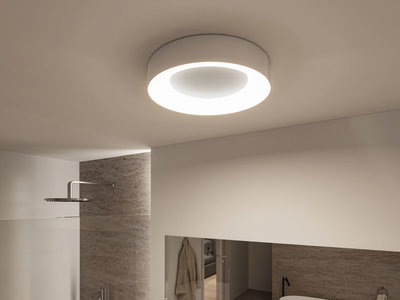 Round white ceiling light with warm white LED ring in modern bathroom featuring natural stone wall.