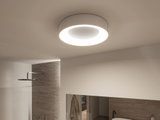 Round white ceiling light with warm white LED ring in modern bathroom featuring natural stone wall.