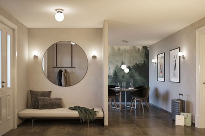 Modern living space with round white LED ceiling and wall lights emitting warm light, stylish interior design.