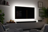 Modernes Wohnzimmer mit schwarzem TV und weißem LED-Hintergrundlicht für stimmungsvolle Beleuchtung.